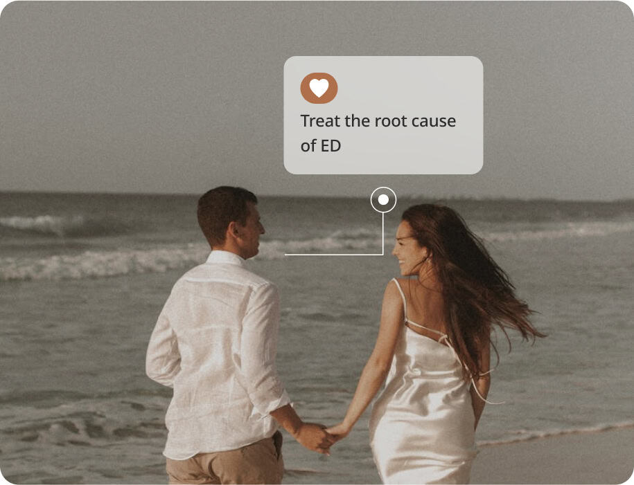A couple holding hands and walking along the beach, both smiling. A text bubble above them reads, Treat the root cause of ED with a heart icon.